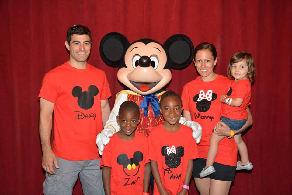 family in matching Disney shirts meeting Mickey at magic kingdom