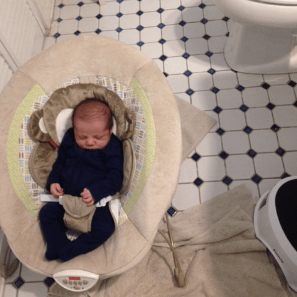 newborn baby sleeping in bouncer on bathroom floor