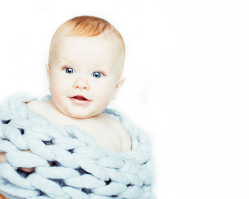 cute modern baby boy in large knit blanket